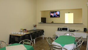 A conference room with a television mounted on the wall, a coffee station, and a table with a green tablecloth. - SIS Hotel (Luanda)