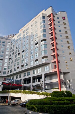 A multi-story hotel with a prominent red vertical feature, multiple balconies, and a clear sky.