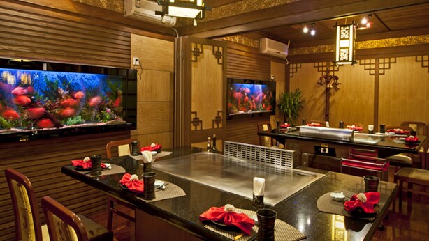 Un restaurante con interiores de madera, acuarios y una plancha central.