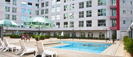 A hotel with a pool area, including lounge chairs and umbrellas.