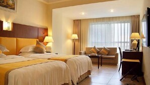 Habitación de hotel con dos camas, un sofá, un escritorio y un televisor.