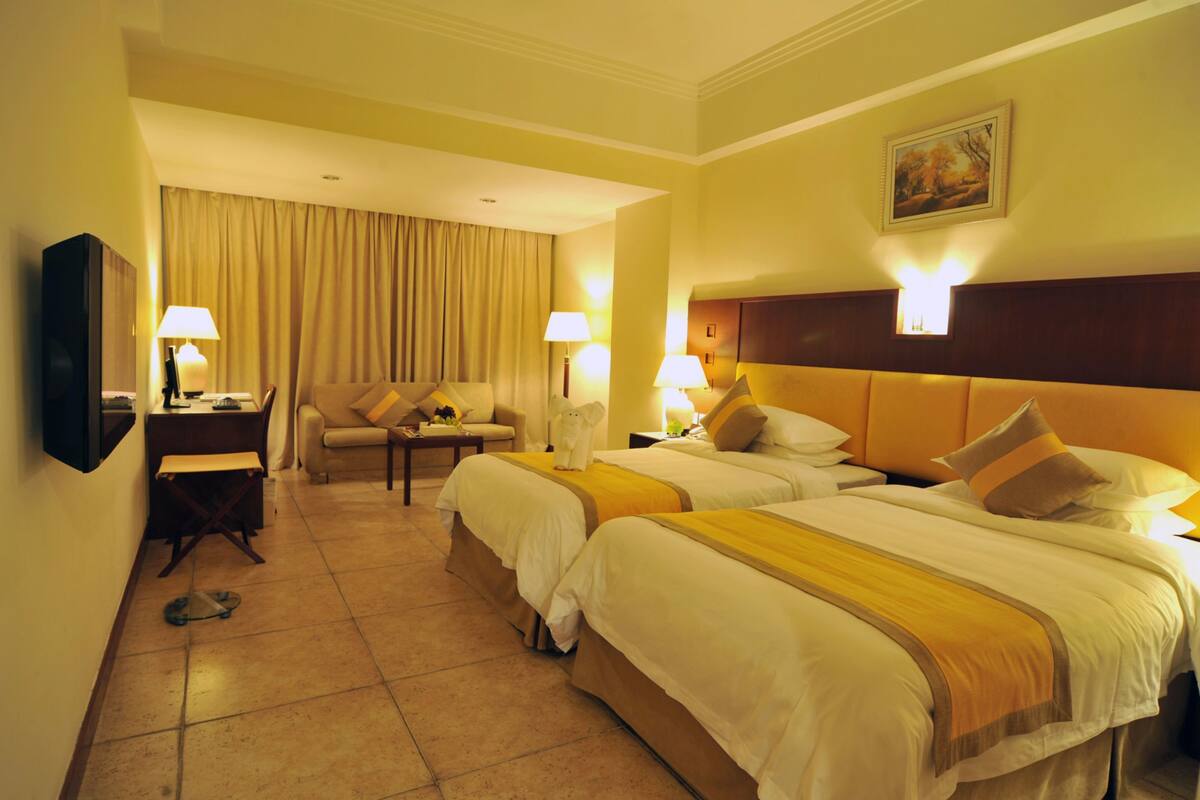 Une chambre d’hôtel avec deux lits, un canapé, un bureau et une télévision.
