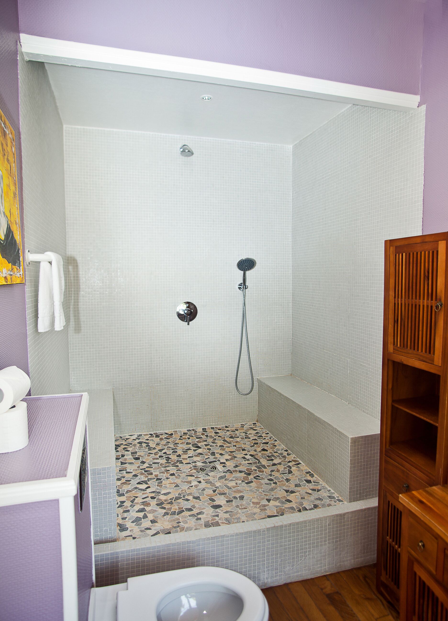 Een badkamer met douche, toilet en een houten kastje.