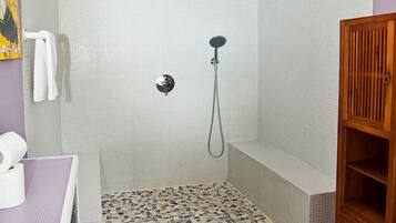Een badkamer met douche, toilet en een houten kastje.