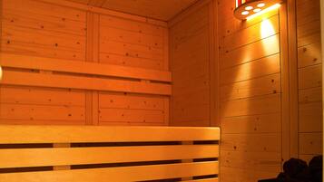 A wooden sauna with benches and a wall-mounted light fixture.