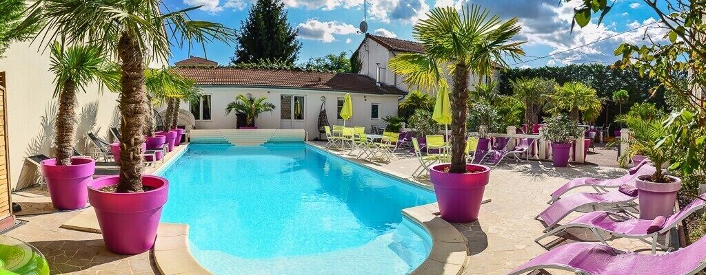 Una piscina con sillones de descanso y plantas en macetas.