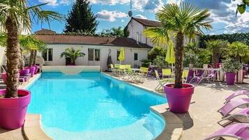 Una piscina con sillones de descanso y plantas en macetas.