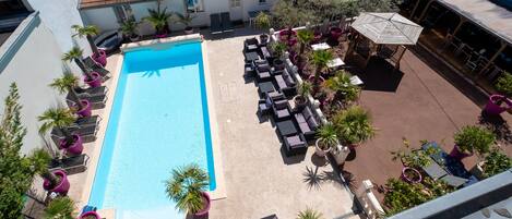 A rooftop swimming pool with lounge chairs and potted plants.
