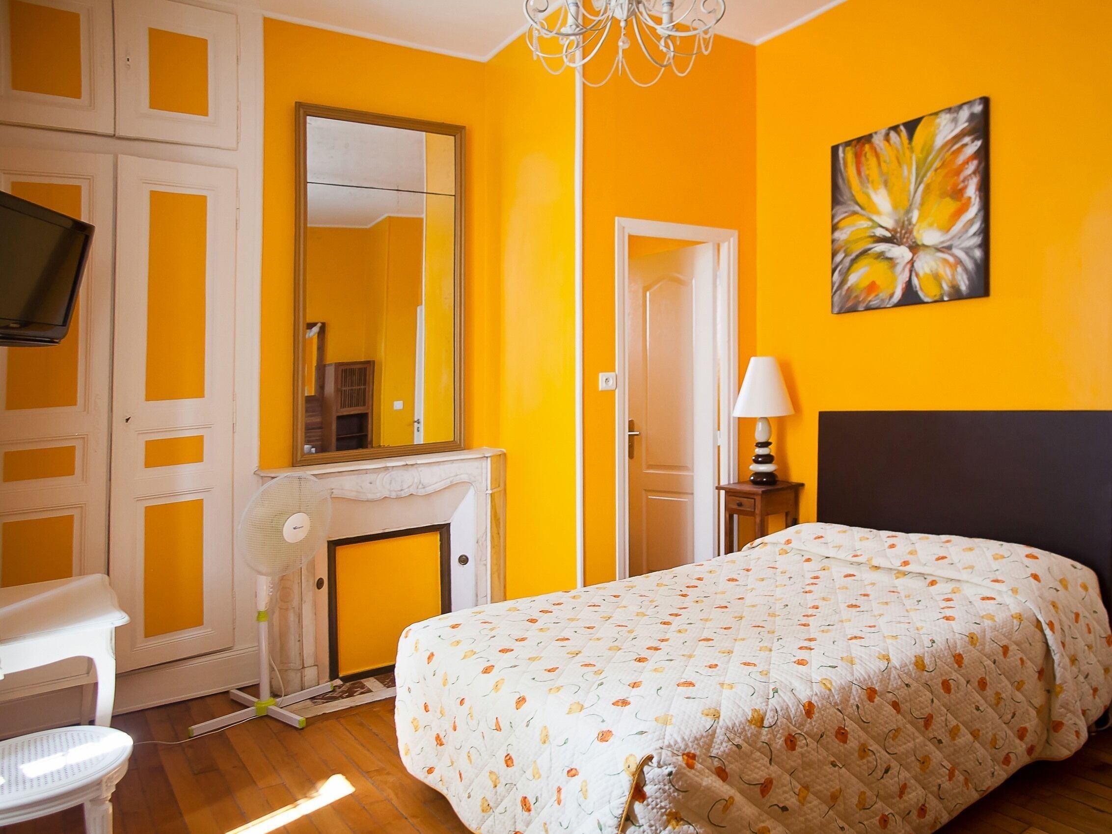 Een slaapkamer met een bed, een televisie, een open haard en een schilderij aan de muur.