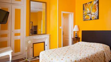 Een slaapkamer met een bed, een televisie, een open haard en een schilderij aan de muur.