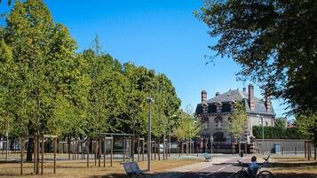 Ein Park mit Bäumen, Bänken und einem Gebäude im Hintergrund.