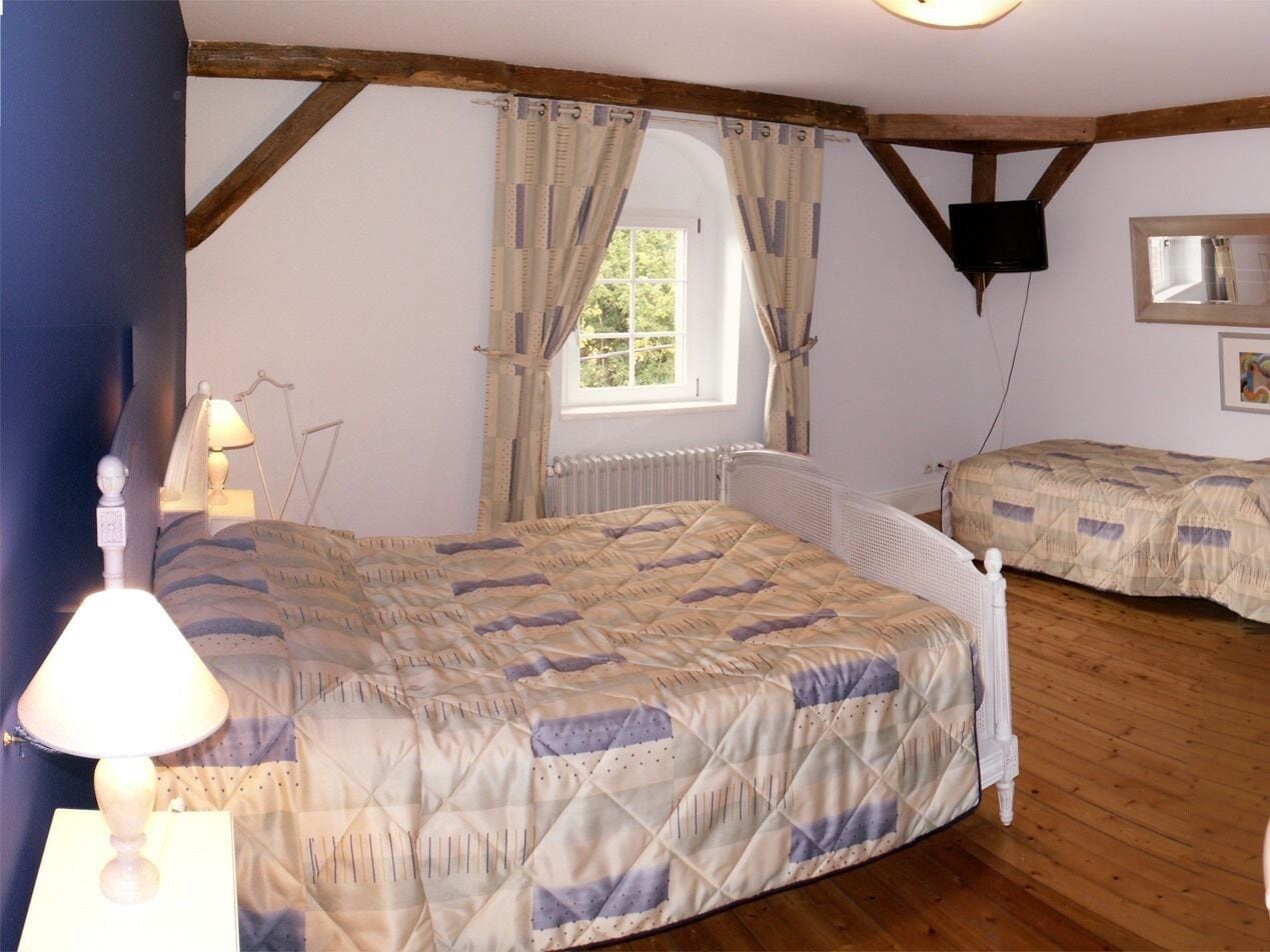 Ein Schlafzimmer mit zwei Betten, einem Fenster, einem Fernseher und einer Lampe.