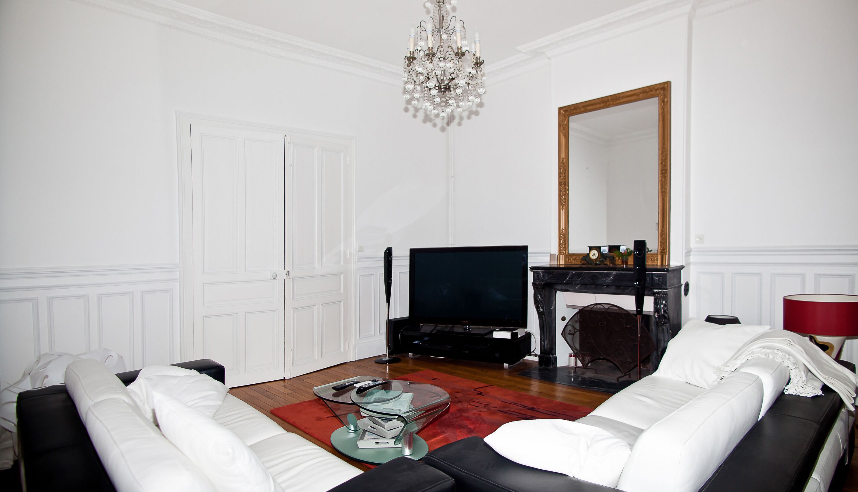 A living room with a sofa, a television, a fireplace, and a chandelier.