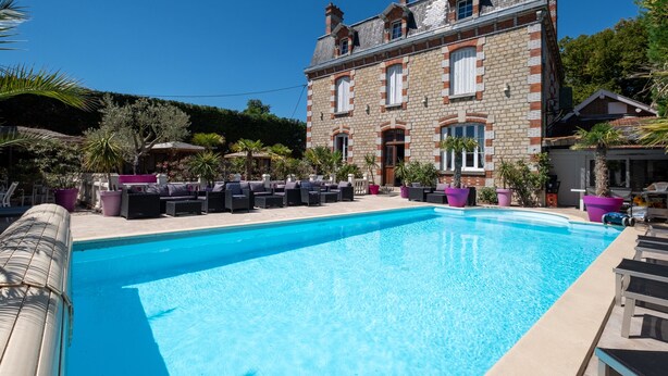 A pool area with lounge chairs and a large stone building in the background. - Manoir François 1er (Vitry-le-Francois)