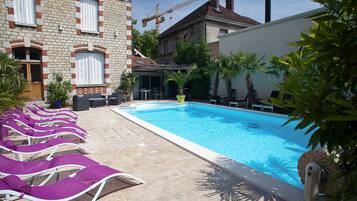 A swimming pool with lounge chairs, a brick building, and a crane in the background.