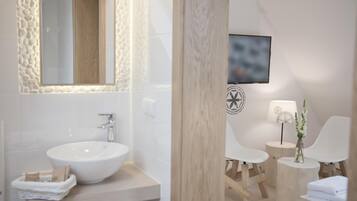 A modern bathroom with a large sink, mirror, and a television mounted on the wall.