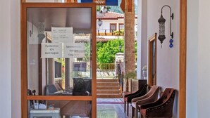 A corridor with a wooden ceiling, a glass display case, and a seating area with chairs.