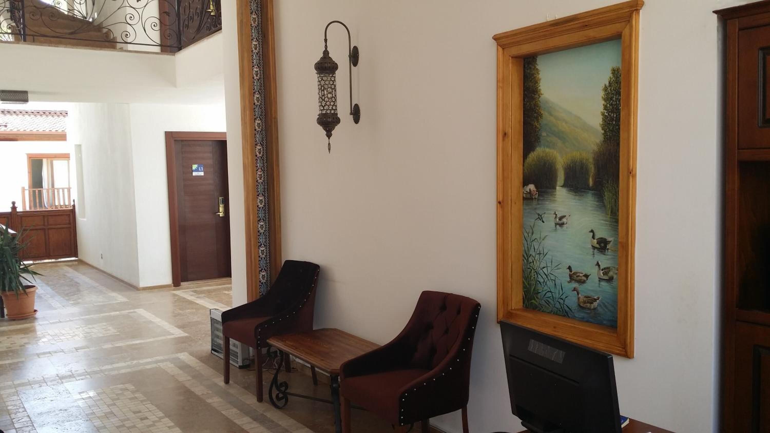 A hallway with a wooden bench, a wall-mounted lamp, and a framed painting of a pond with ducks.