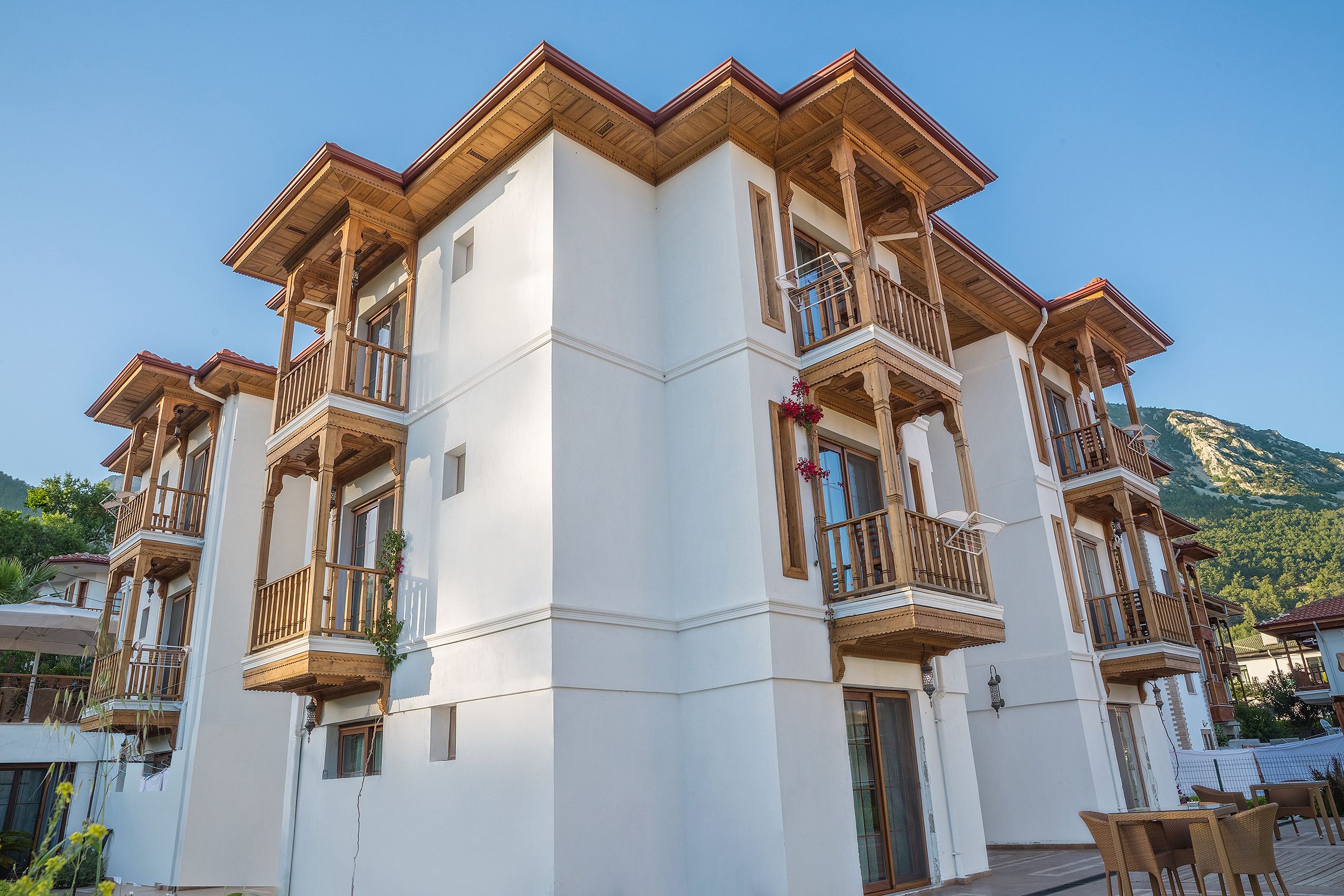 Un hotel de varios pisos con balcones y un paisaje montañoso de fondo.