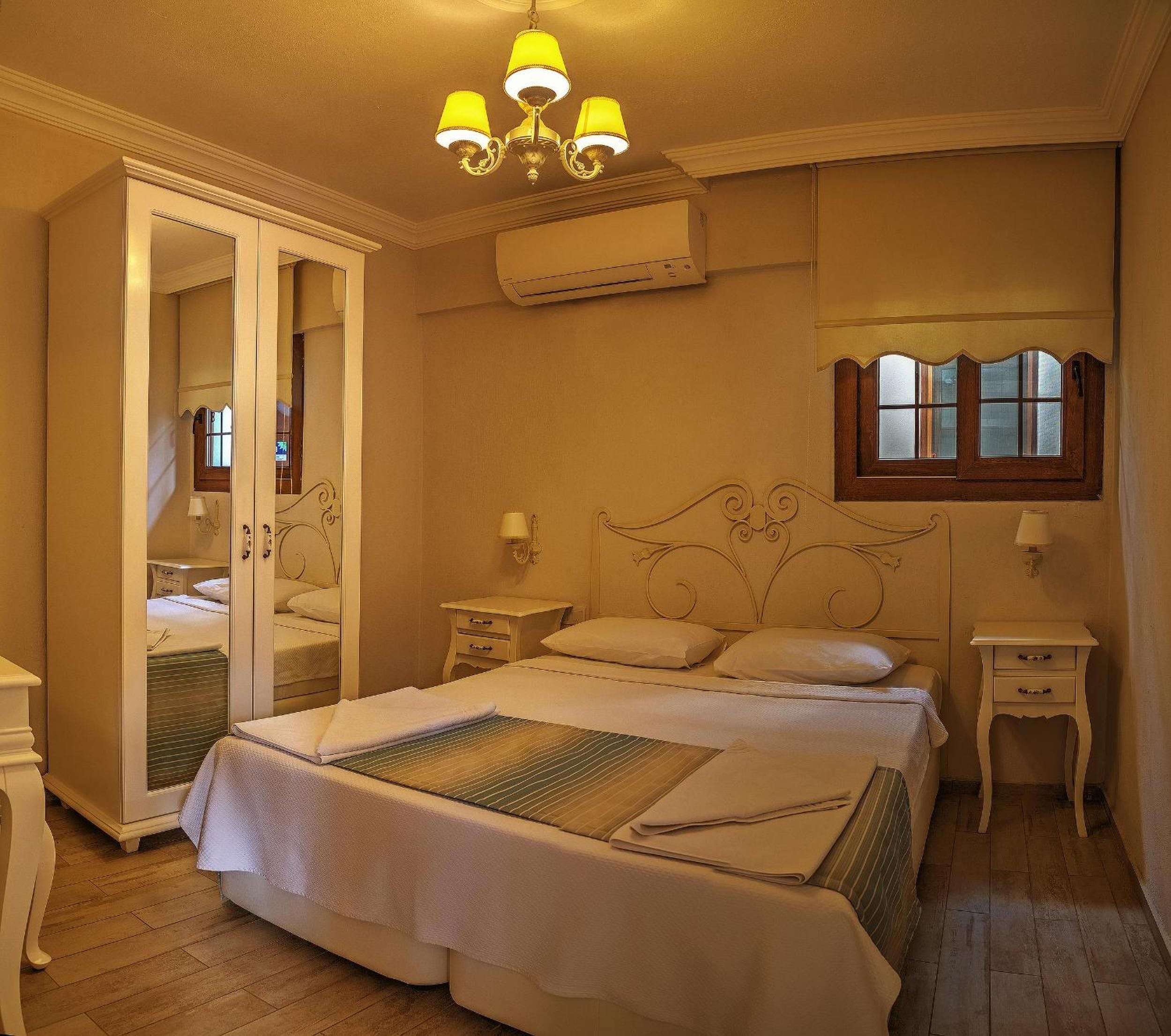 A neatly arranged bedroom with a bed, bedside tables, a wardrobe, and a window.