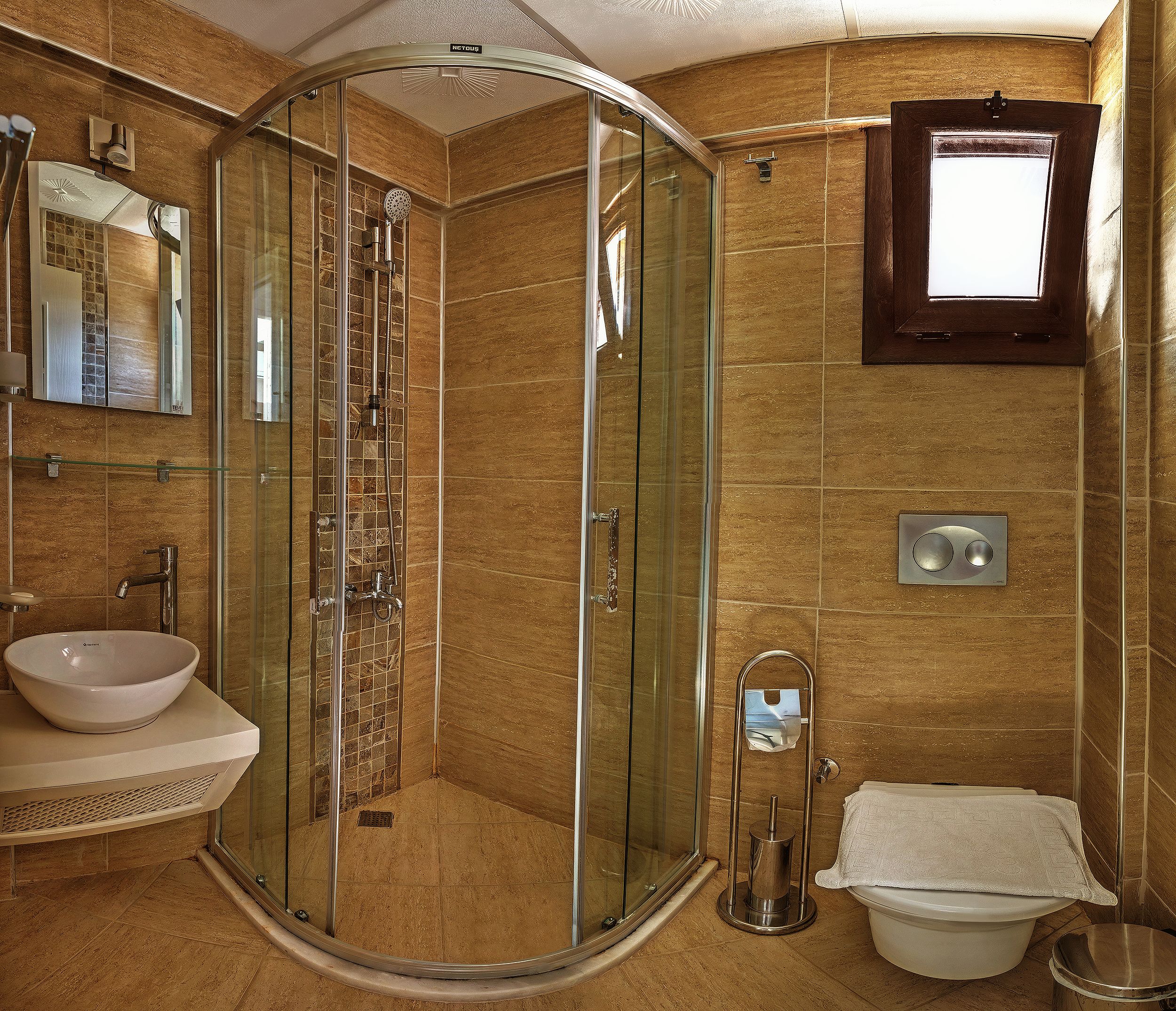 A modern bathroom with a glass-enclosed shower, a sink, and a toilet.