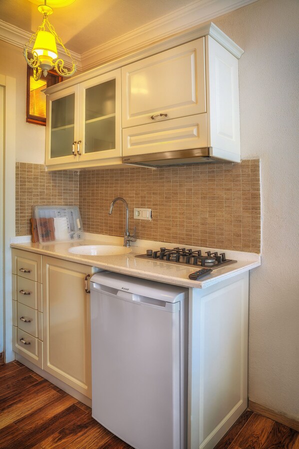 A compact kitchen with white cabinetry, a built-in stove, and a sink.