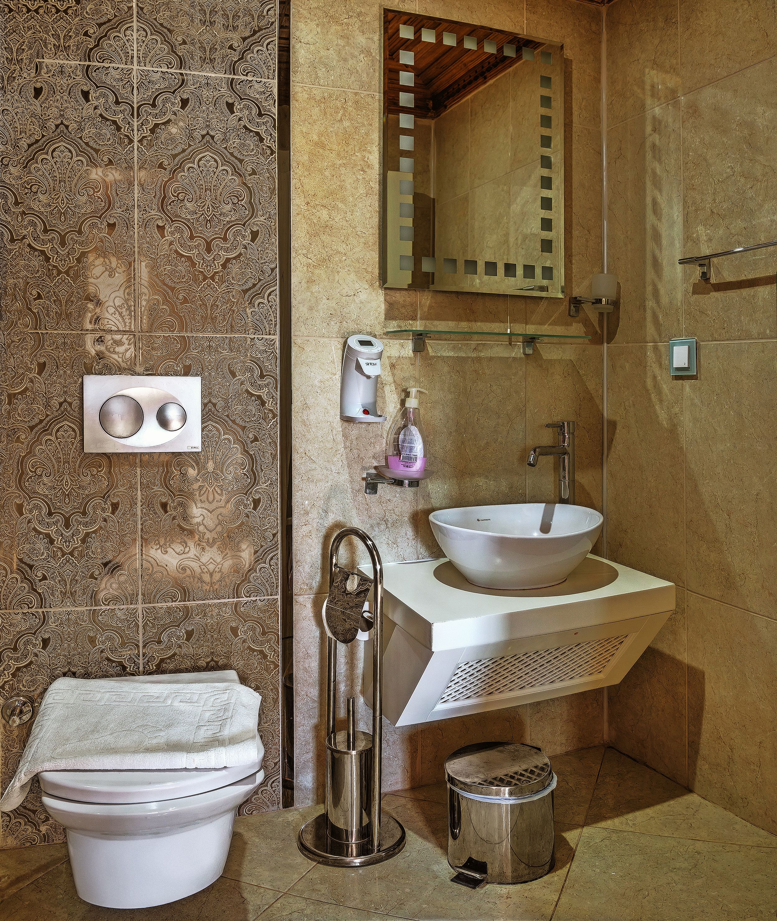 A bathroom with a toilet, bidet, sink, mirror, and towel rack.
