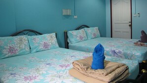 A room with two beds, each with floral bedding, a blue wall, and a door.