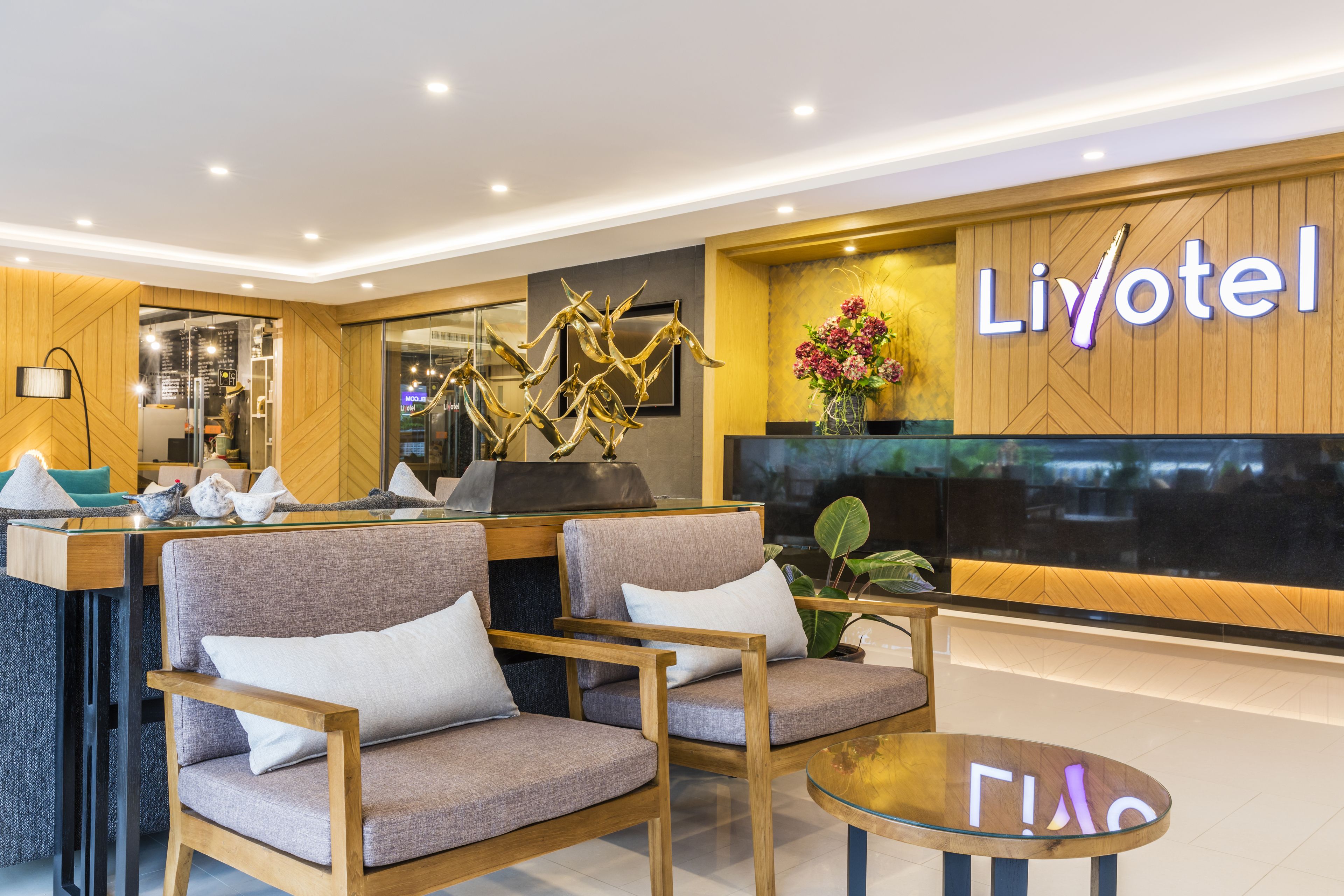 A modern hotel lobby with a reception desk, comfortable seating, and a prominent 'Liyotel' sign.
