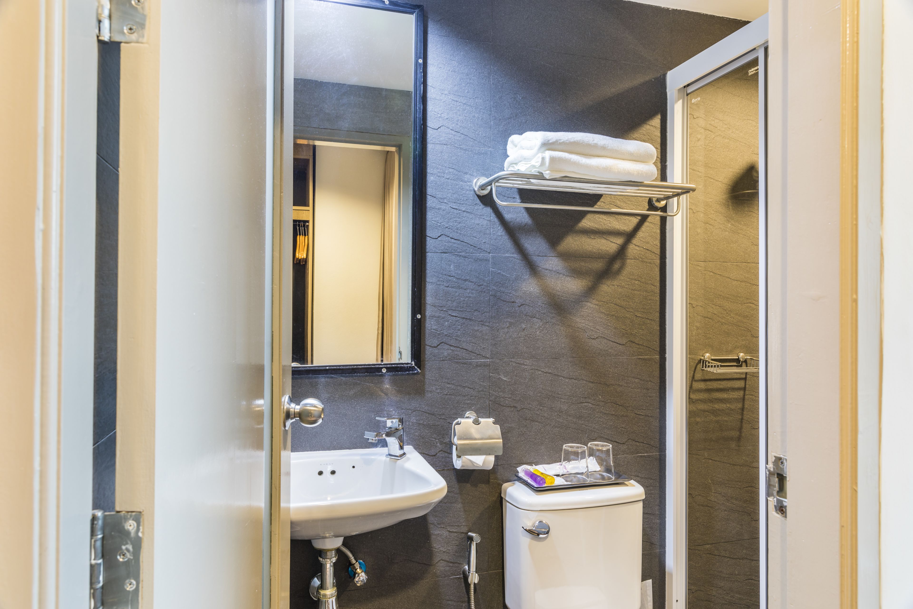 A bathroom with a white sink, a mirror, a towel rack, and a toilet.