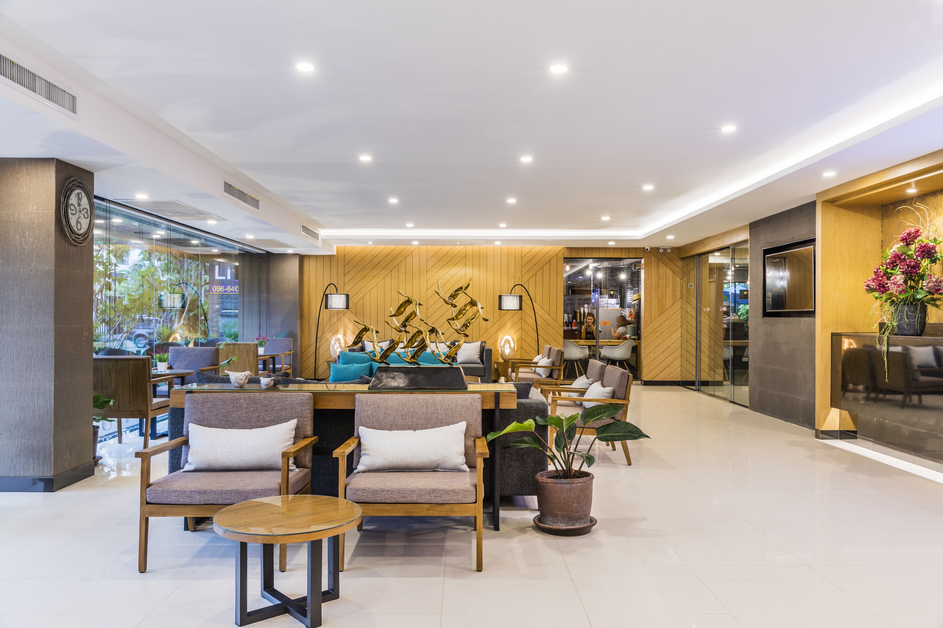 A modern hotel lobby with wooden paneling, comfortable seating, and a reception desk.