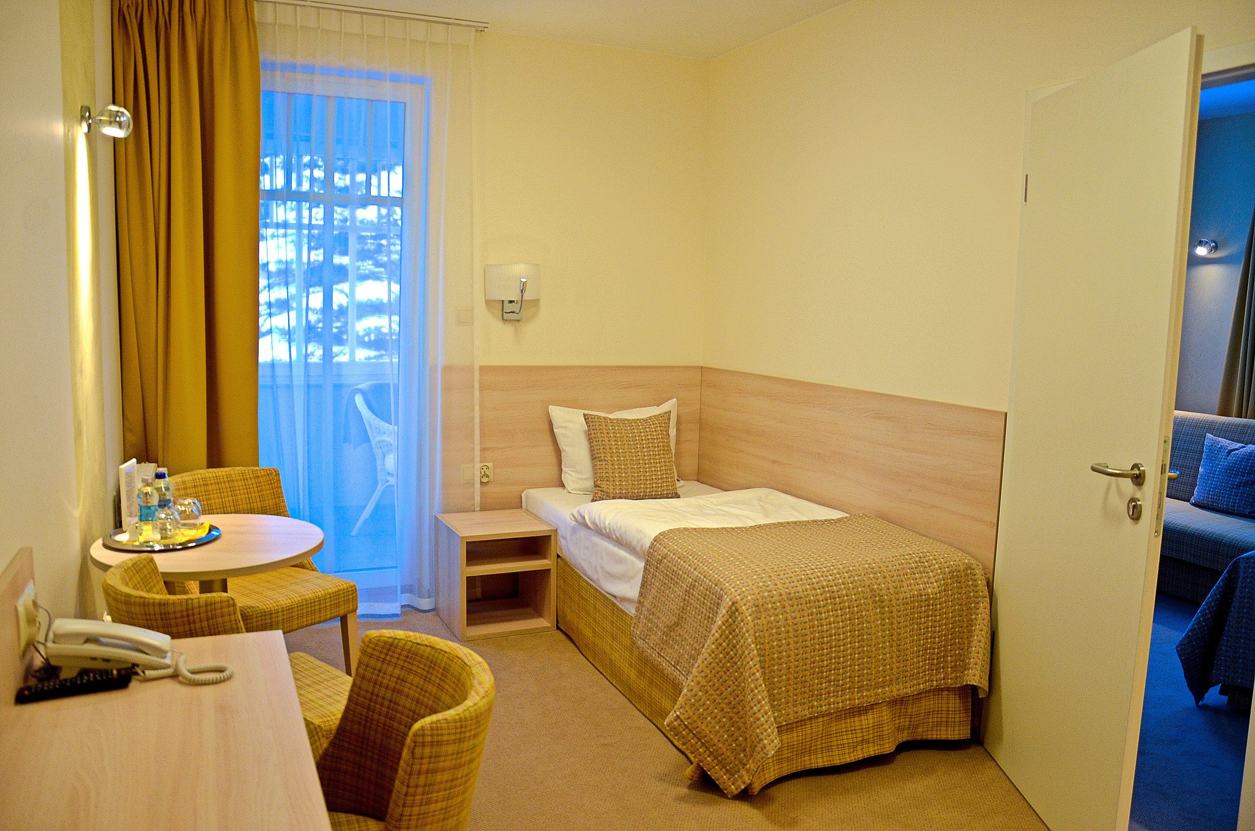 Une chambre d’hôtel comprenant un lit, une petite table avec des chaises, une table de chevet et une vue sur l’extérieur par une fenêtre.