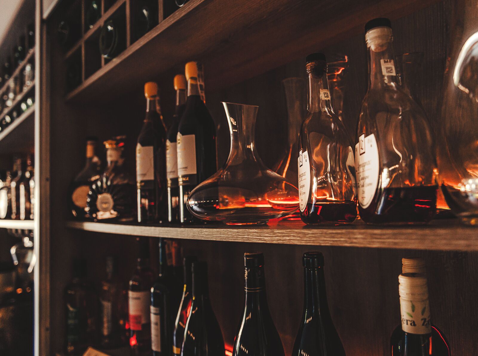 Una estantería de bar con diferentes botellas y vasos, probablemente conteniendo bebidas alcohólicas.
