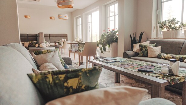 Uma sala de estar espaçosa com um sofá grande, uma mesa de centro com um jogo de tabuleiro e um espaço de jantar com cadeiras e mesa.