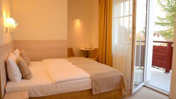 A hotel room with a bed, a small table with a lamp, and a sliding glass door to the outside.