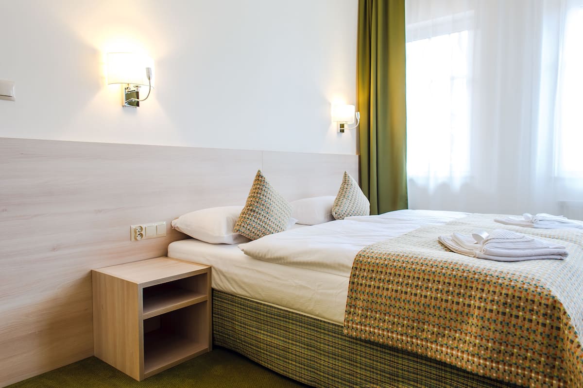 A hotel room with a bed, a nightstand, and two wall-mounted lights.