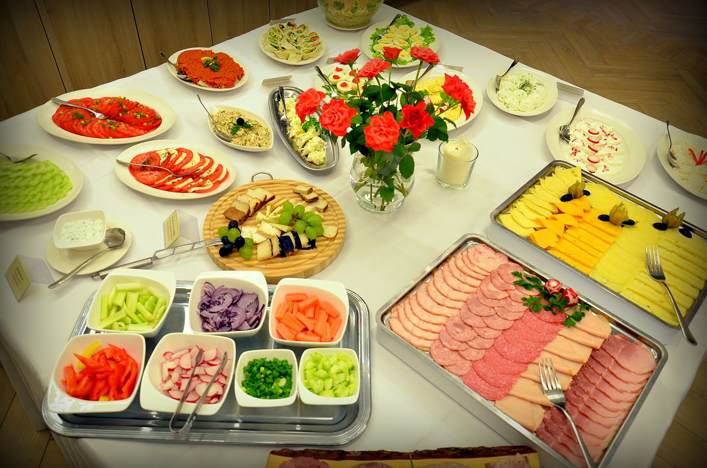 Una mesa de buffet con diferentes opciones de comida y un jarrón de rosas rojas.