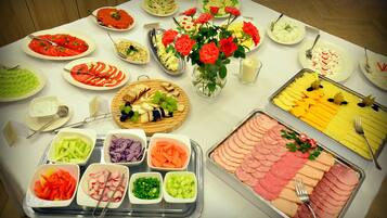 Una mesa de buffet con diferentes opciones de comida y un jarrón de rosas rojas.