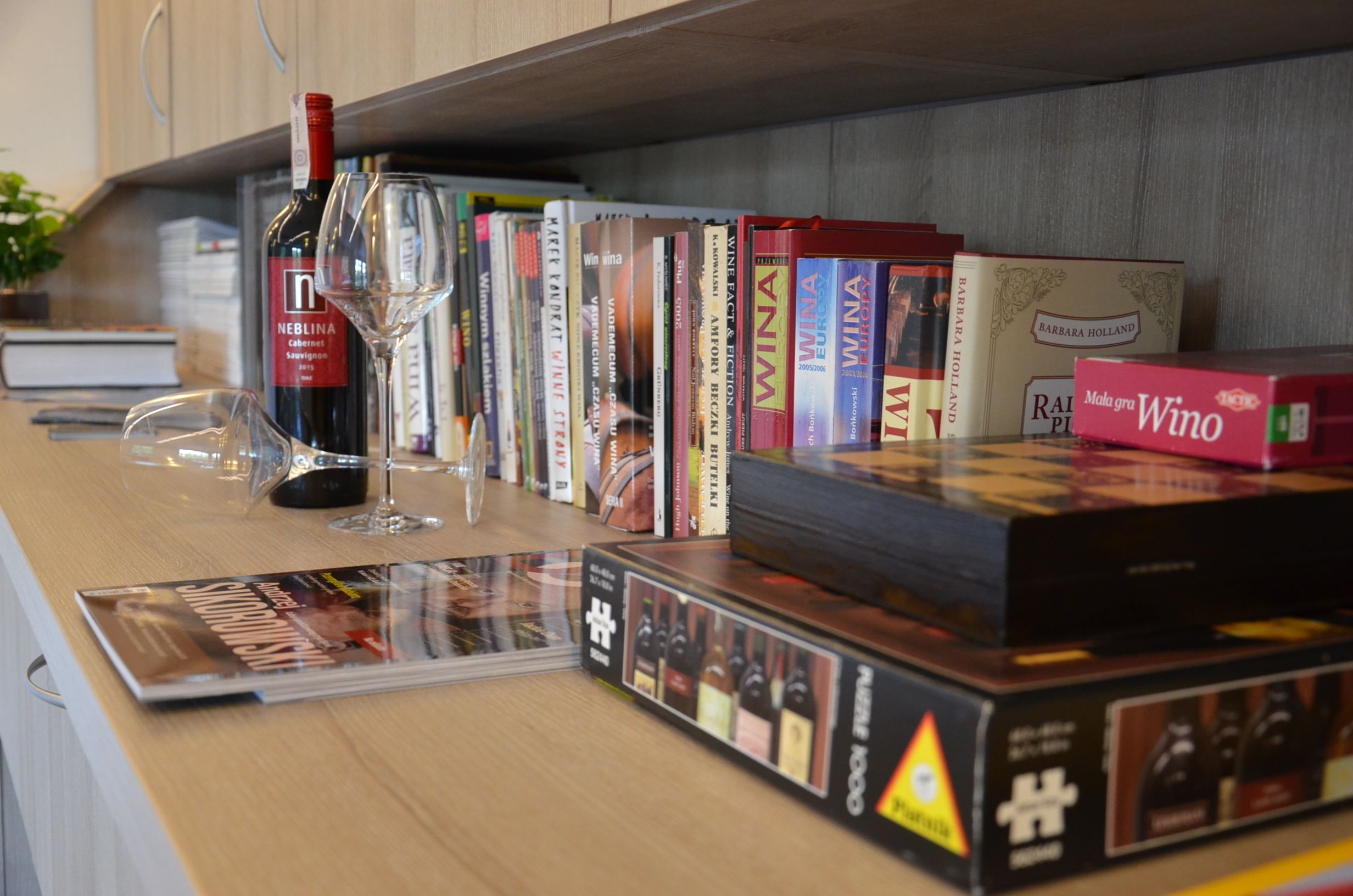 A wine rack with various bottles and a wine glass on a wooden surface.