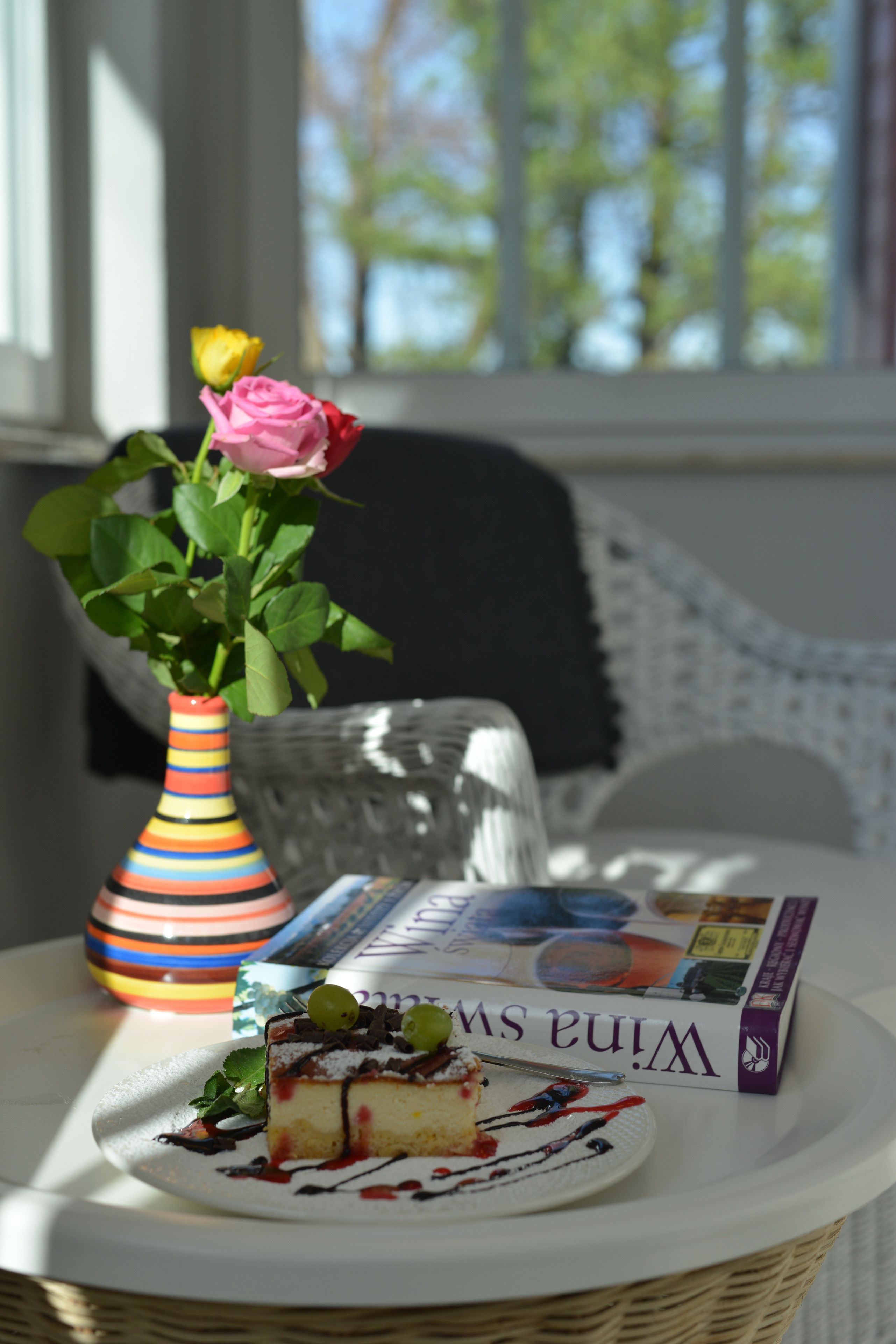 A table with a slice of cake, a vase with flowers, and a book titled "Wina Swanson."