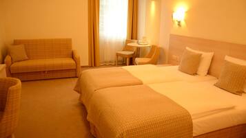 Een hotelkamer met twee bedden, een bank en een kleine tafel.