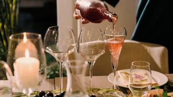 Una mesa servida con copas de vino, una vela y una botella siendo vertida.