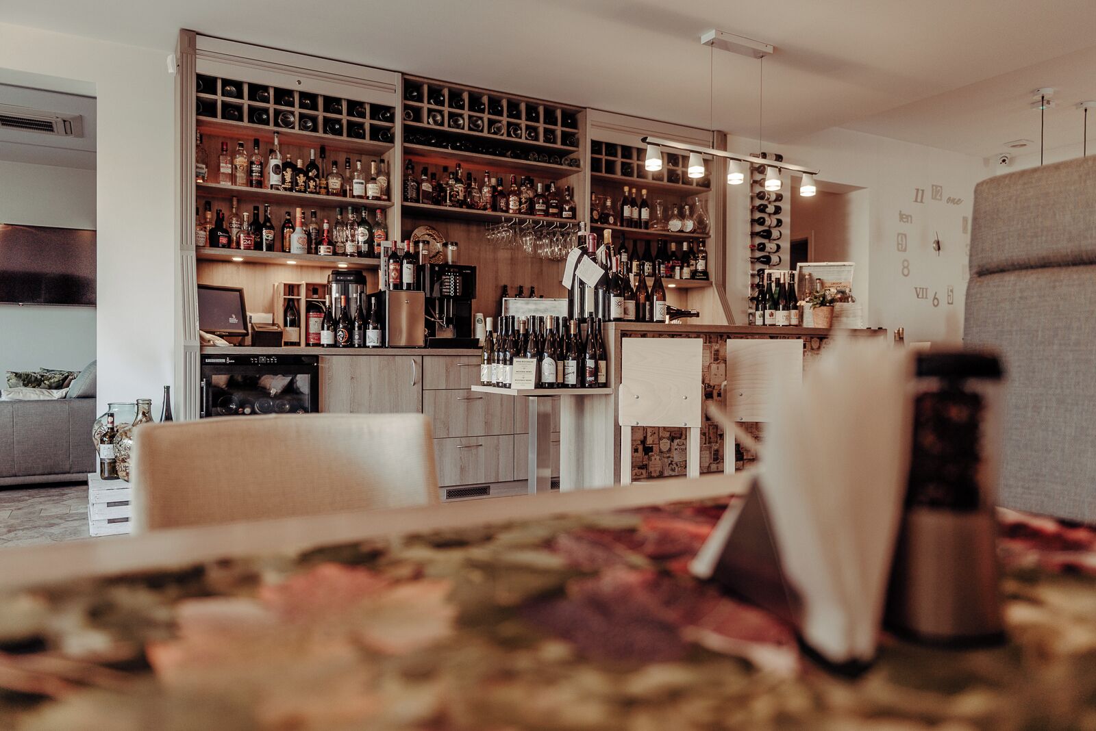 A bar area with shelves of bottles and glasses, a refrigerator, and a counter.