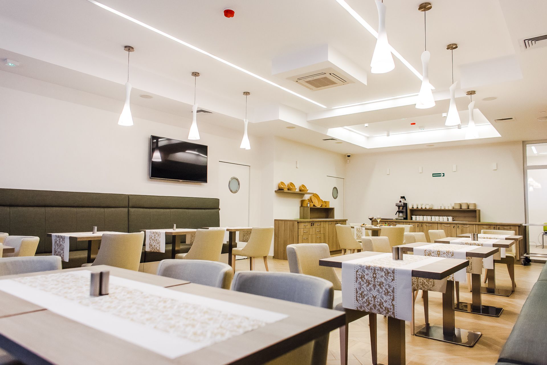 A modern restaurant with high ceilings, pendant lighting, and a central kitchen area.