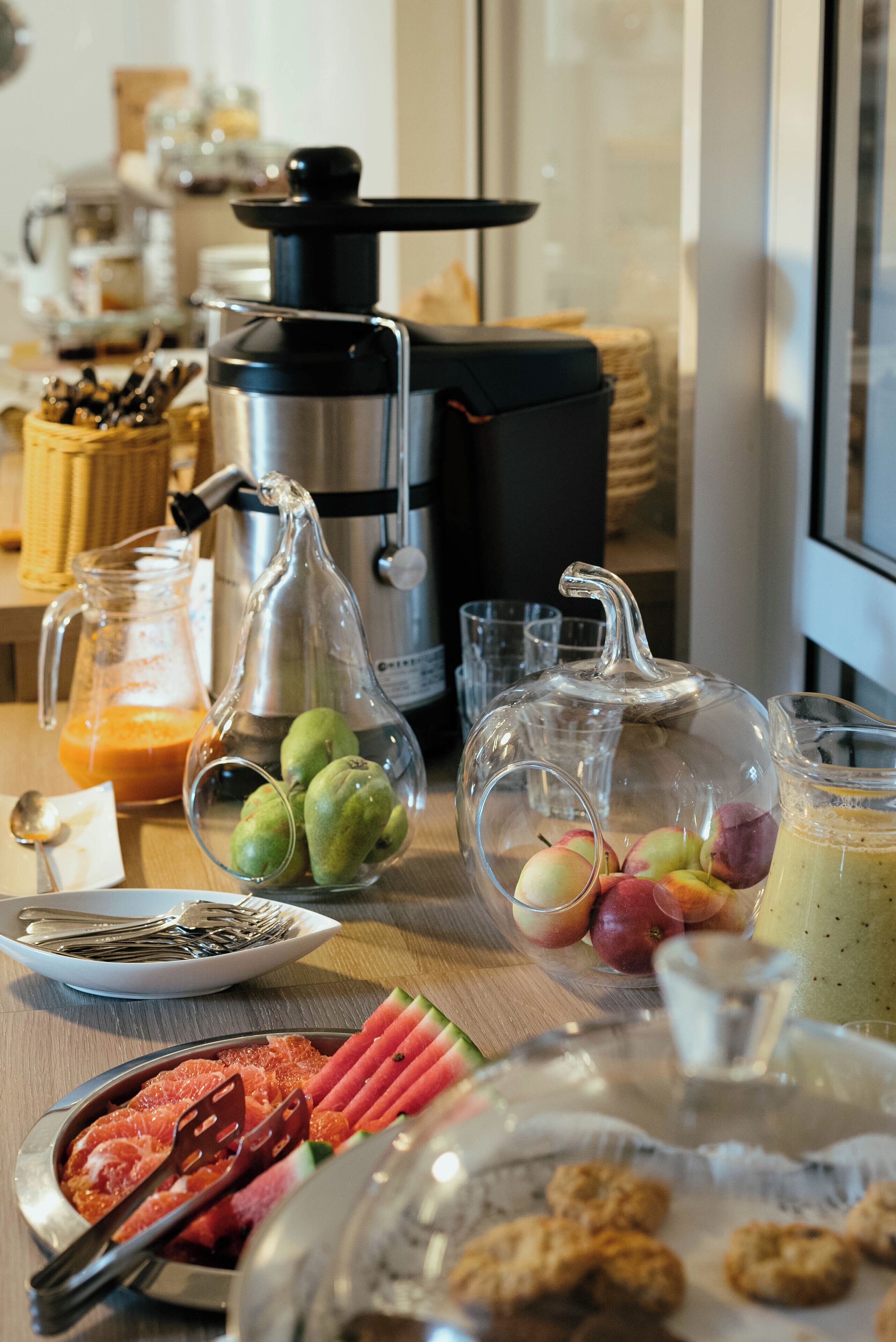 Uma mesa de café da manhã com diversos alimentos, uma cafeteira e uma fruteira.