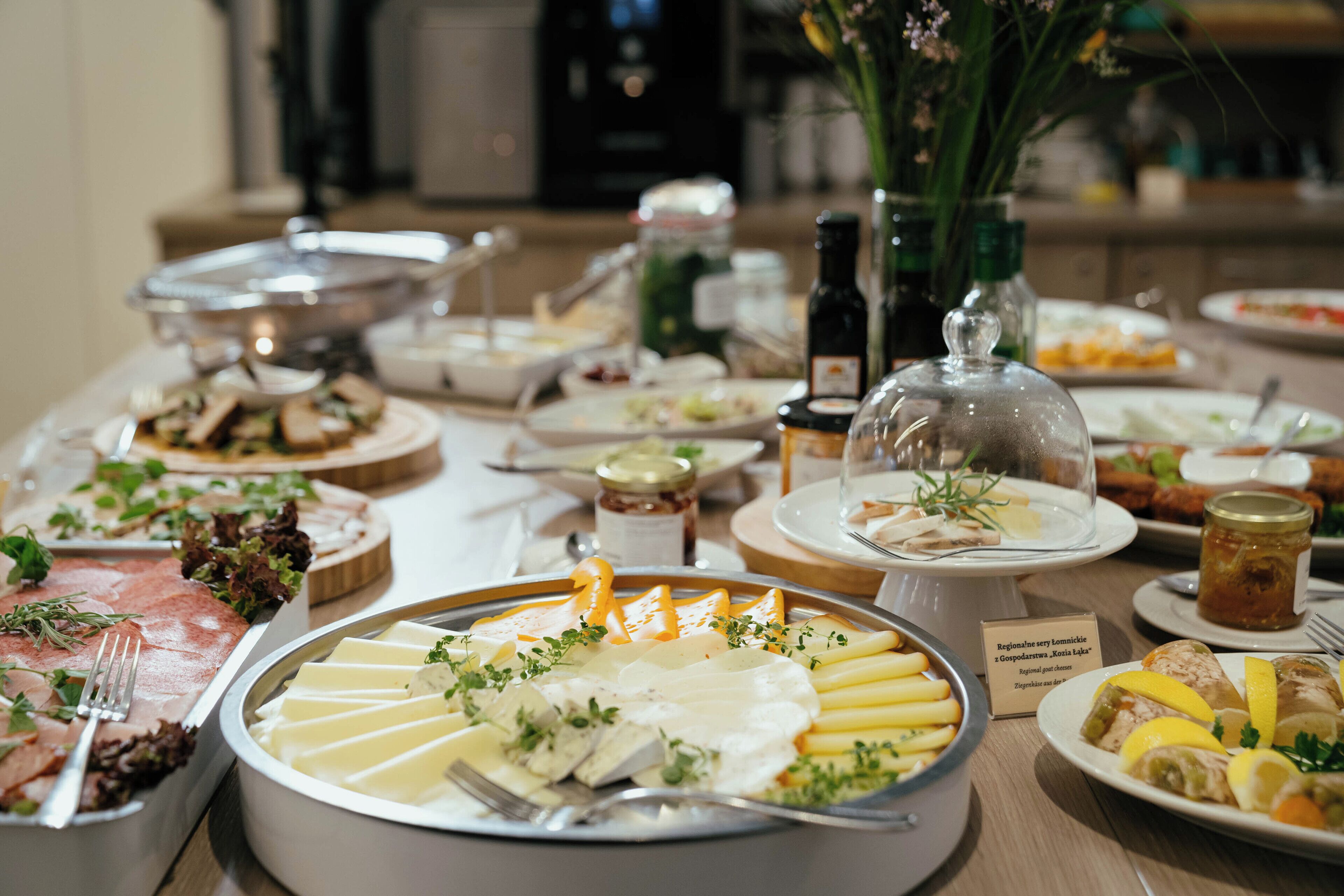 Une table de buffet proposant divers plats, notamment un assortiment de fromages, des salades et des viandes.