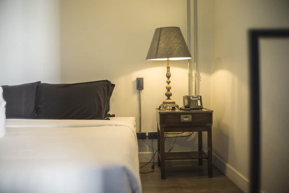A hotel room with a bed, a bedside table with a lamp, and a telephone.
