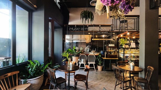 A cozy cafe interior with wooden furniture, potted plants, and a chalkboard sign reading "Music is my religion." - Iron32 Hotel (Chiang Mai)