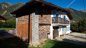 A chalet with a stone facade, wooden balcony, and a view of mountains. - Chamonix Lodge (Chamonix-Mont-Blanc)