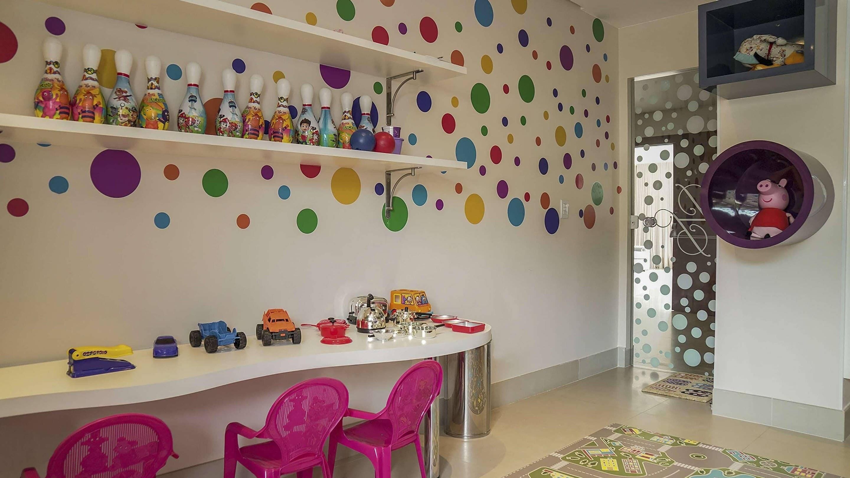 A children's playroom with colorful bowling pins, toy cars, and a pink chair.